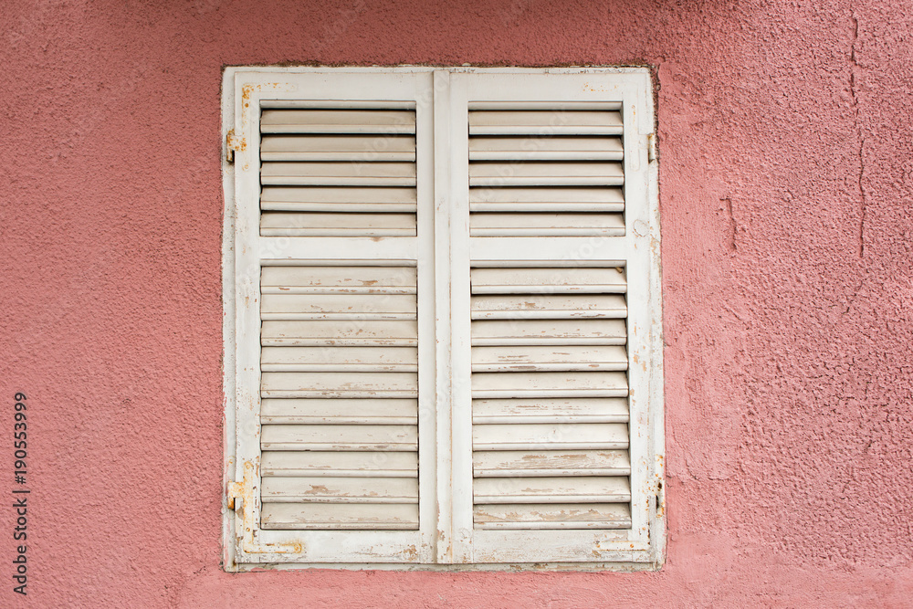 Wooden window with shutters on a pink wall