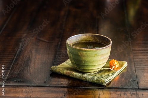A green tea cup on rustic wood table.