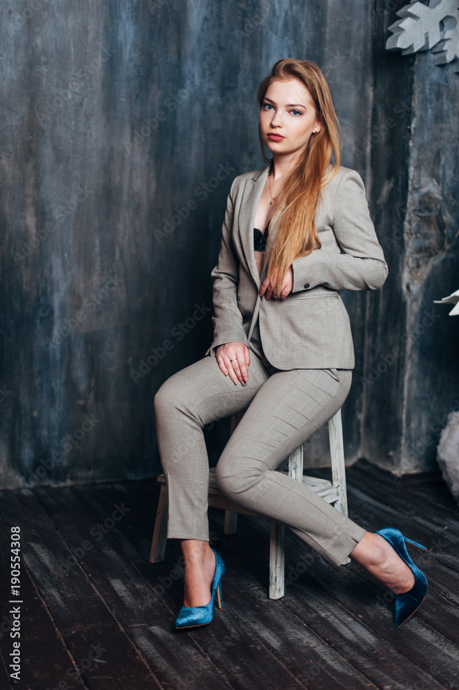A beautiful girl in a gray suit is sitting on a chair in a Christmas decor. A beautiful girl in a gray suit is sitting on a chair in a Christmas decor.