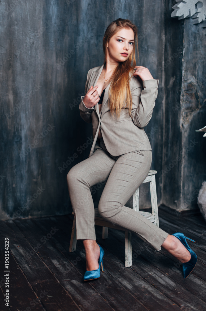 A beautiful girl in a gray suit is sitting on a chair in a Christmas decor. A beautiful girl in a gray suit is sitting on a chair in a Christmas decor.