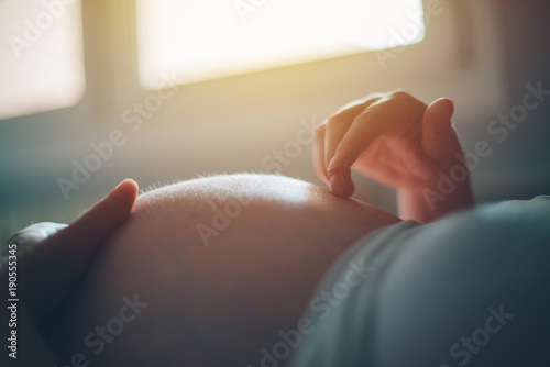 Canvastavla Pregnant woman cuddling belly in bedroom at home