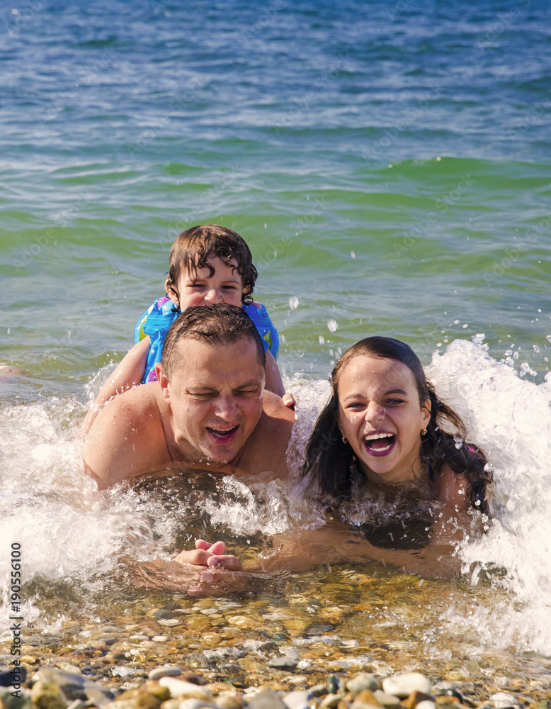 Cute boy and girl with father on the sea beach in the resort Cute boy and girl with father on the sea beach in the resort