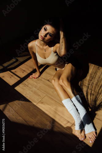 Beautiful modern ballet dancer with perfect body sits on the floor in the studio hall.