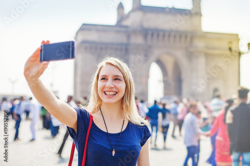 Obraz na plátně Caucasian woman posing in front of Gateway of India in Mumbai and taking selfie