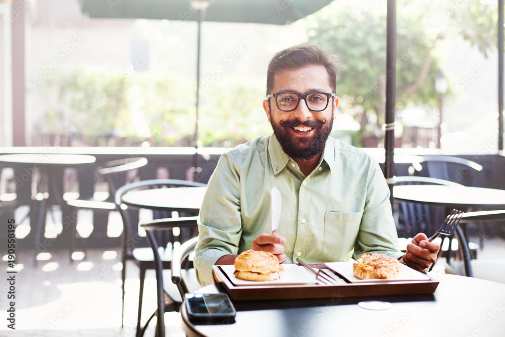 Young bearded indian man having breakfast in a cafe Young bearded indian man having breakfast in a cafe