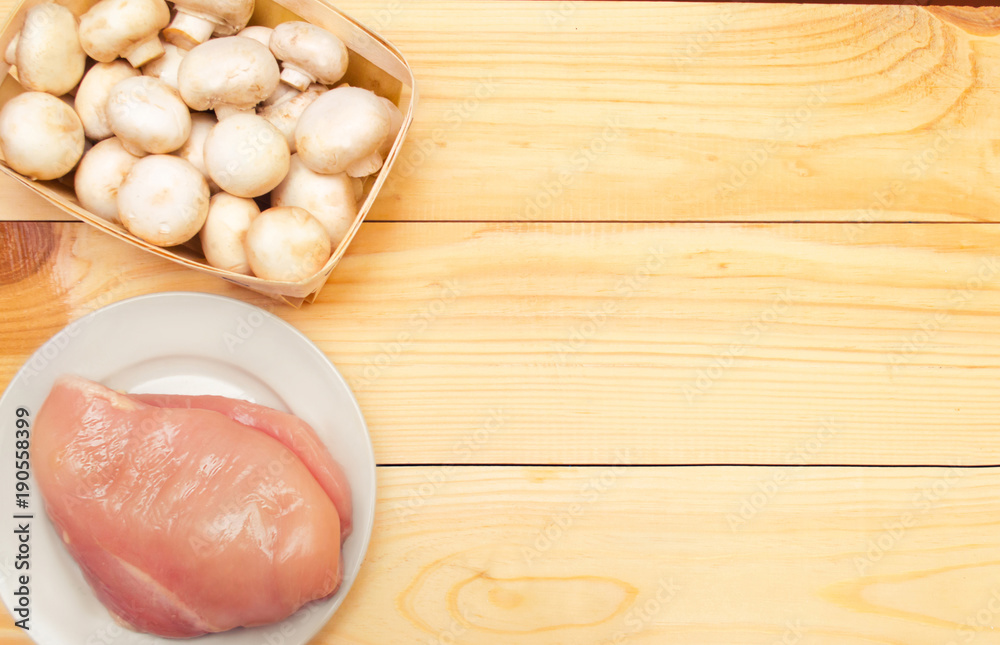 raw chicken fillet and mushrooms on a wooden background. place for text