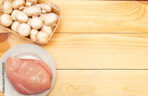 raw chicken fillet and mushrooms on a wooden background. place for text