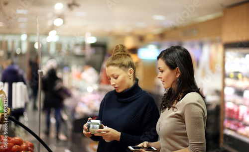 Two women choosing a dairy products at supermarket