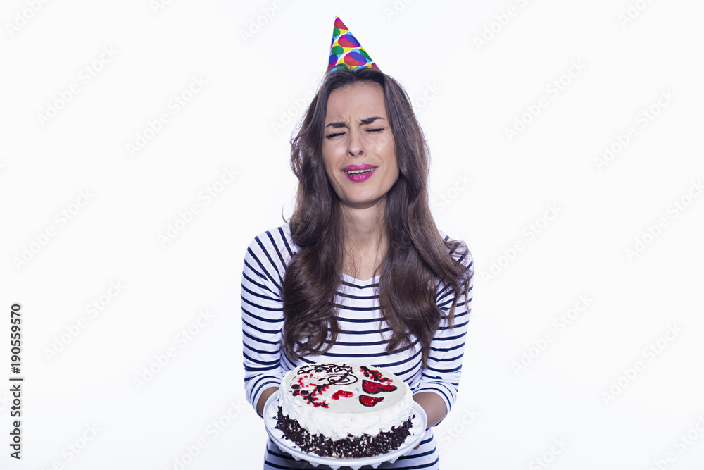 Beautiful birthday girl holding a big cake but refusing it isolated on a white background. Beautiful birthday girl holding a big cake but refusing it isolated on a white background.