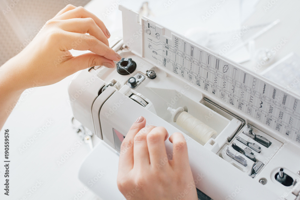 Fototapeta premium Seamstress adjusts the sewing machine to work