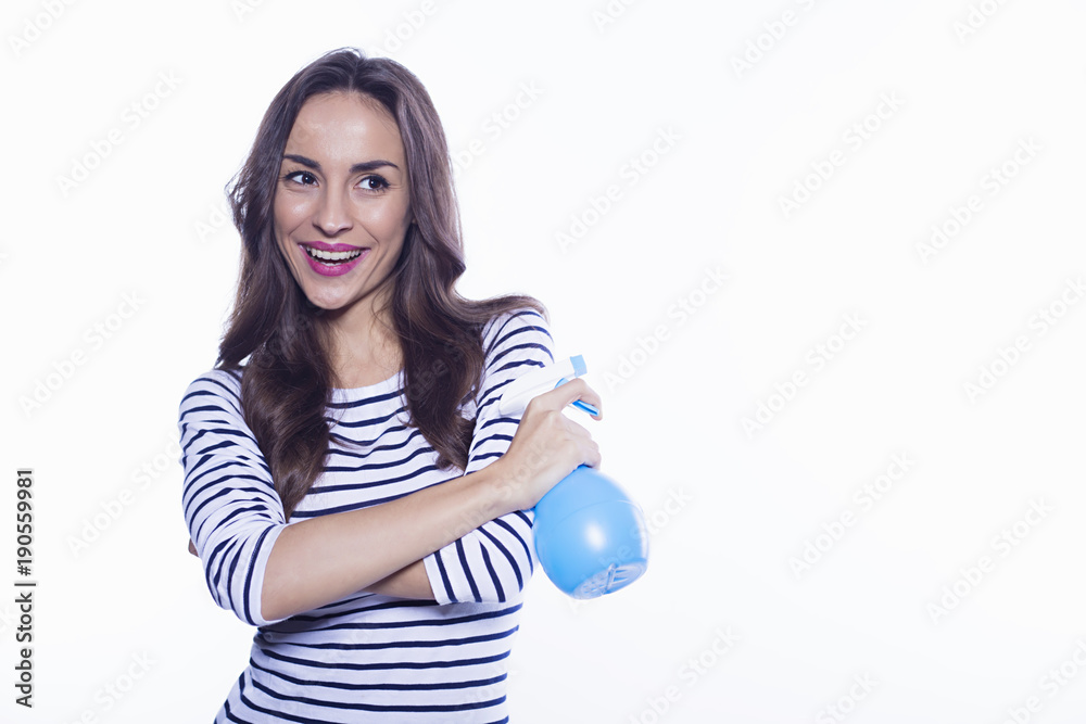 House cleaning. A cheerful beautiful and energetic young woman with a nebulizer in her hands is cleaning her apartment. Means to clean glass. House cleaning. A cheerful beautiful and energetic young woman with a nebulizer in her hands is cleaning her apartment. Means to clean glass.