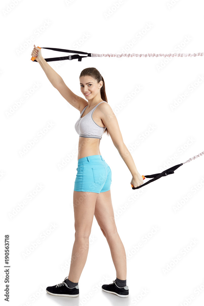 Young beautiful girl in sports uniform is engaged on a simulator with an expander. Young beautiful girl in sports uniform is engaged on a simulator with an expander.