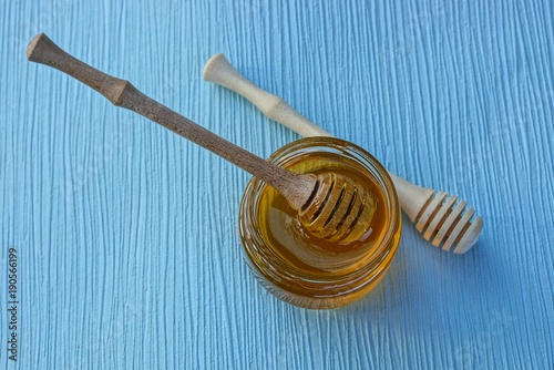 деревянная ложка в банке с мёдом на синем столе
