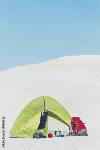 Journey through the desert with a backpack and tent. The tent is on a sandy crest. © vetal1983