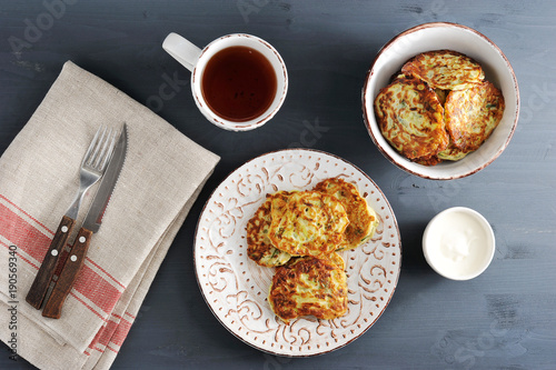 fritters of zucchini with tea on rustic wooden background w
