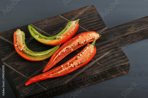 red and green chili peppers cut in half on wooden Board