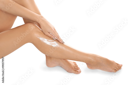 Woman applying body cream on her leg against white background, closeup