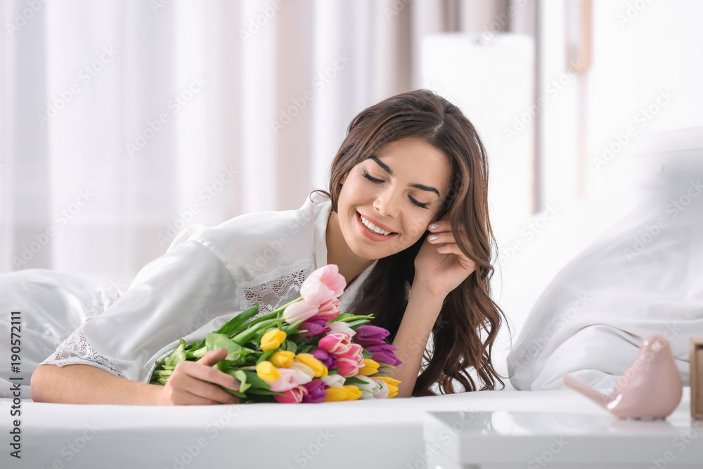 Beautiful woman with bouquet of tulips on bed at home Beautiful woman with bouquet of tulips on bed at home