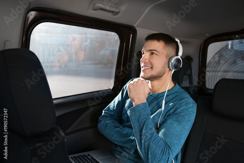 Man listening to audiobook through headphones in car © Africa Studio