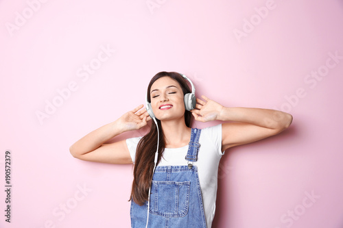 Woman listening to audiobook through headphones on color background