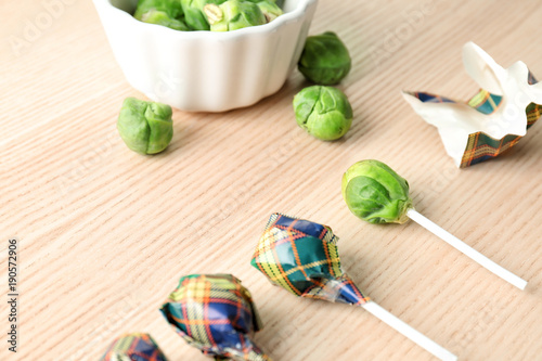 Fényképezés Brussel sprouts with lollipop sticks in candy wrappers on table