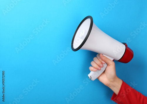 Woman holding megaphone on color background