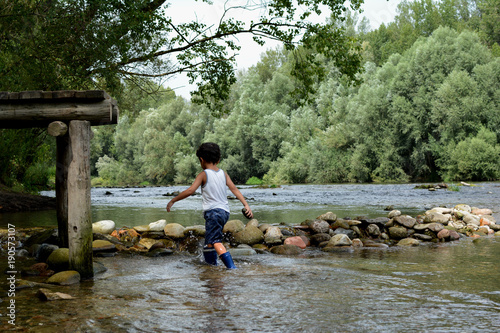CHILD PLAYING WITH ROCKS AT THE RIVER