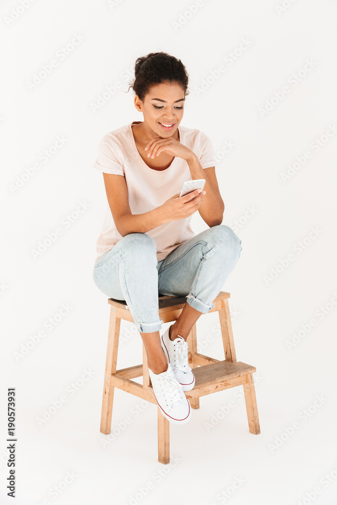 Portrait of woman in casual sitting on chair and holding mobile phone in hands, isolated over white background Portrait of woman in casual sitting on chair and holding mobile phone in hands, isolated over white background