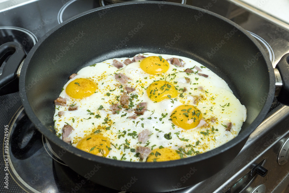Fried eggs in a deep frying pan with bacon.