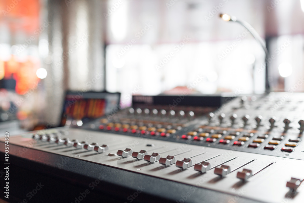 Fototapeta premium od adjusters and red buttons of a mixing console. It is used for audio signals modifications to achieve the desired output. Applied in recording studios, broadcasting, television.