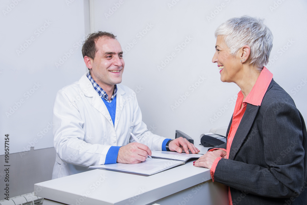 Senior woman paying her medical bill at the clinic with her credit card Senior woman paying her medical bill at the clinic with her credit card