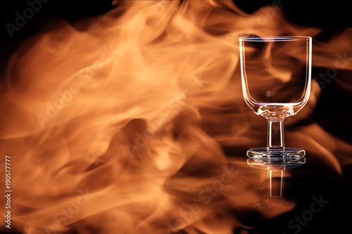 Photo An empty glass of port or sherry in the fire flames.