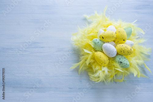 Colorful Easter Eggs in yellow feathers nest.