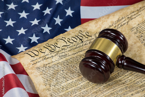 wooden court gavel on United States Constitution document and American flag