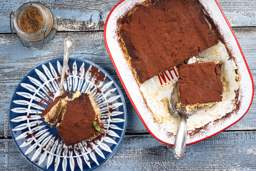 Traditional Italian tiramisu as top view on plate and in backing form photo