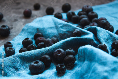 Close up of blueberries on a blue linen cloth draped.