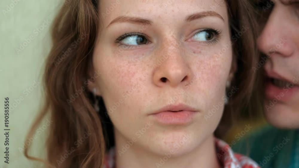 A man whispers in the ear of a woman, emotions on her face A man whispers in the ear of a woman, emotions on her face