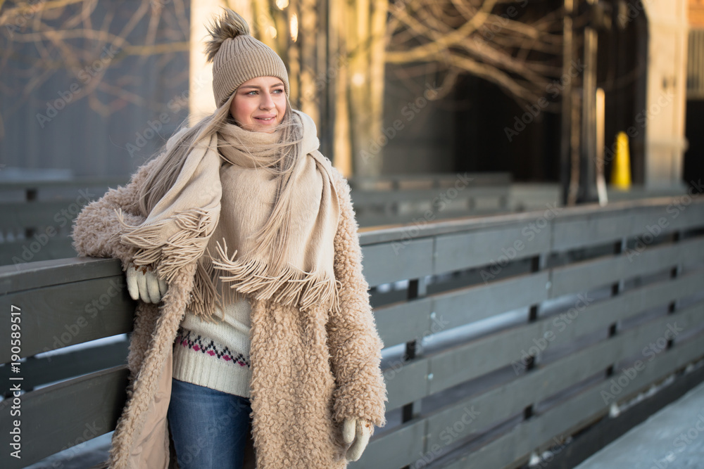 Full length portrait of young female with blonde hair in fur coat, beige hat,  scarf and