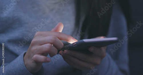 Woman sending sms on cellphone in the evening at night