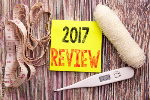 2017 Review. Business fitness health concept for Annual Summary Report written sticky note empty paper background with copy space bandage and thermometer photo