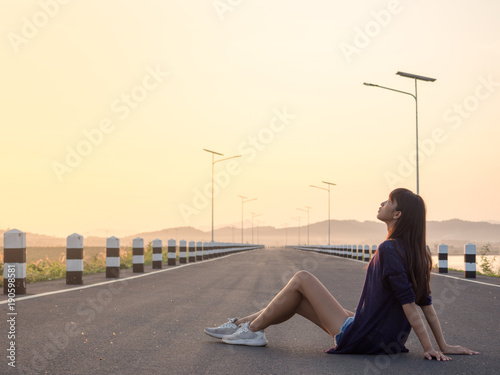 Young asian woman sitting on the road at sunrise