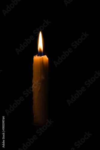 One light candle burning brightly in the black background