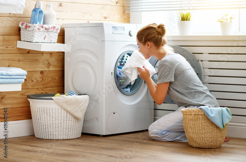 Happy housewife woman in laundry room with washing machine photo