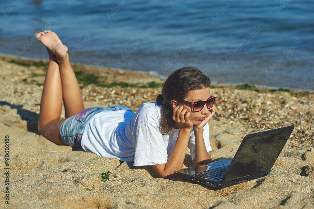 Young woman on beach with laptop .The use of technology on vacation