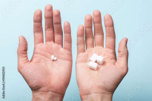 Choice of Sweetener in tablets or regular sugar. Alternative to sugar for diabetics. A man holds sugar in one hand in another sugar sauce in tablets. photo
