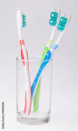 colorful toothbrushes in a glass on background.