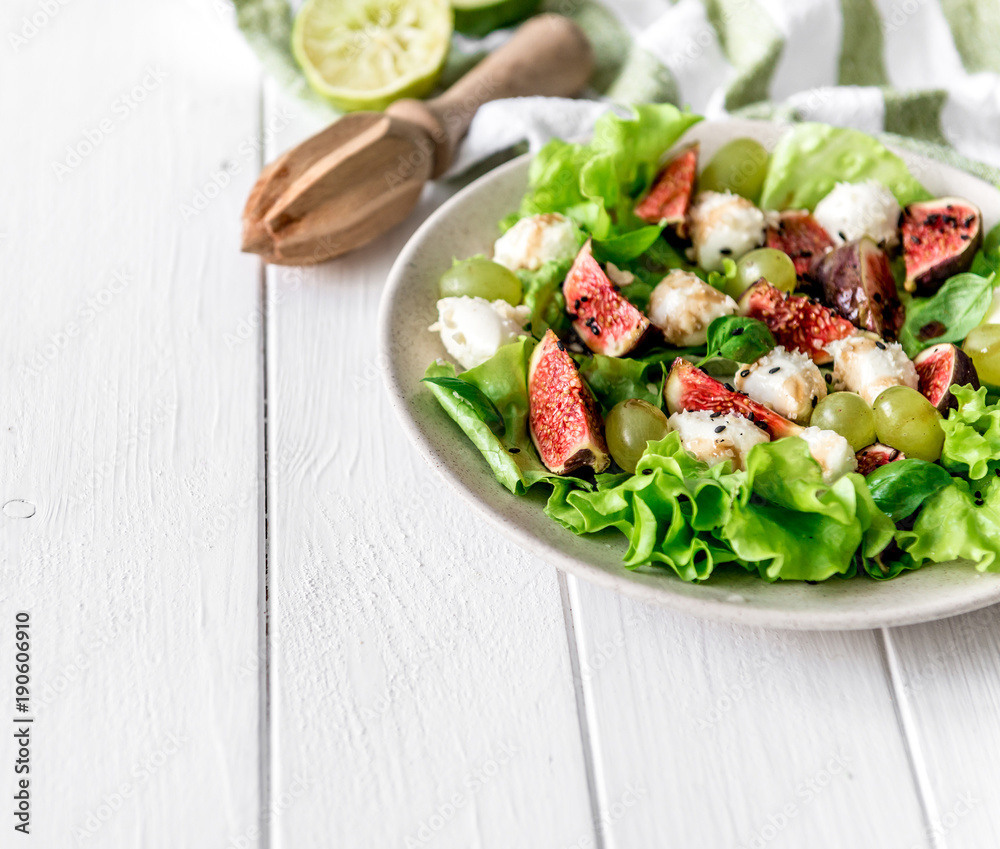 Salad with figs, mozzarella and grapes on a white wooden background. Salad with figs, mozzarella and grapes on a white wooden background.