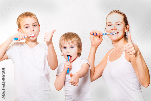 family mom and two blond boys brush their teeth