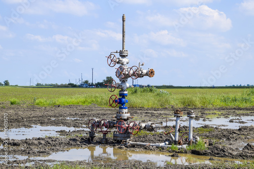 Oil well after repair in mud and puddles. Oil well wellhead equipment. Hand valve with handwheel for opening and closing the flow line photo