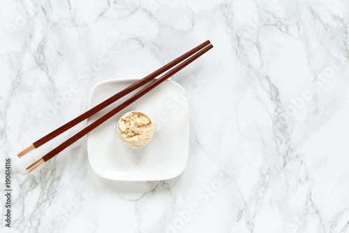 Protein powder in scoop on small plate with chopsticks against marble background